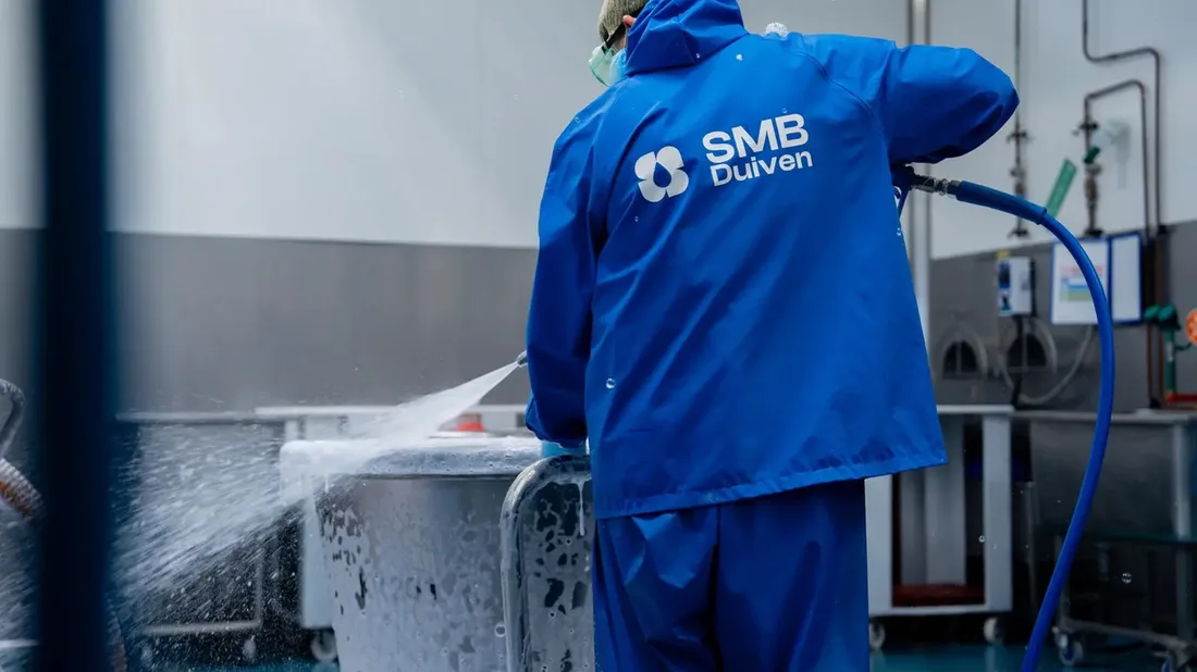Medewerker van SMB Duiven in blauwe werkkleding met het nieuwe logo, aan het werk met een hogedrukreiniger